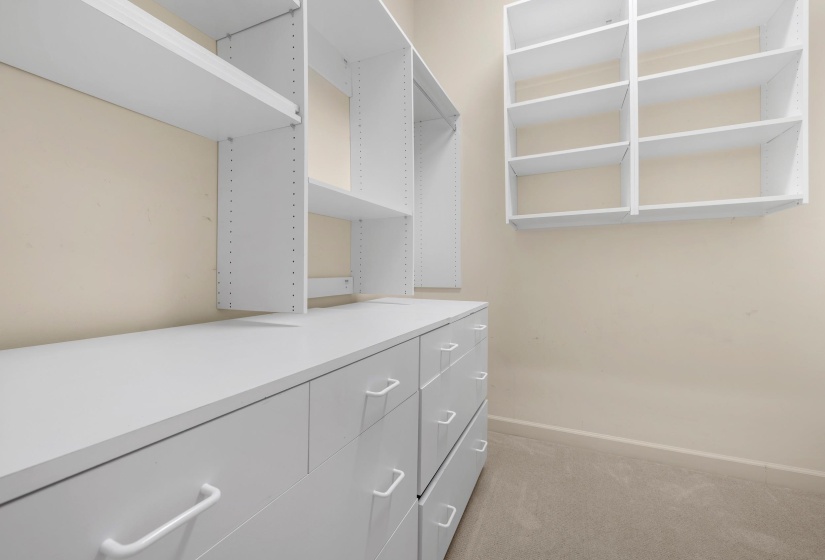 Built-in white storage system featuring drawers, shelving, and hanging space