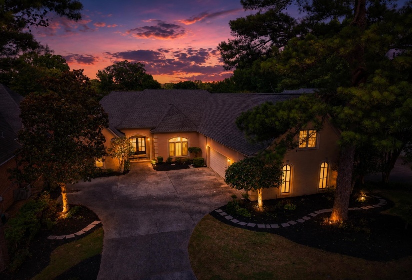 Stucco exterior residence with a concrete driveway, multi-pane front door, and arched windows