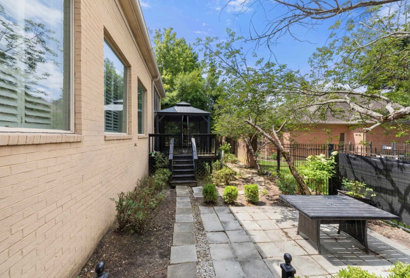 Outdoor living space featuring a stone paver patio, established landscaping, and a fenced perimeter