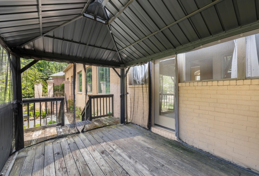 Expansive screened-in porch featuring a metal-paneled roof, wood-finish flooring, and black railing