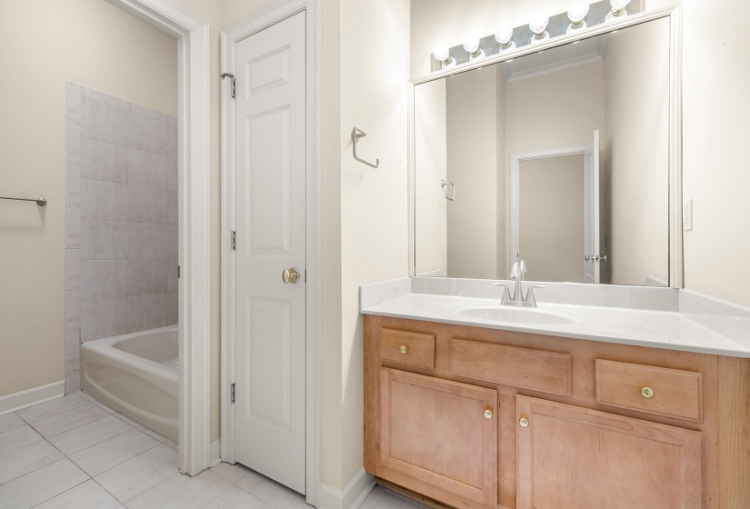 Bathroom featuring a single vanity with wood cabinetry, a white countertop, and a large mirror