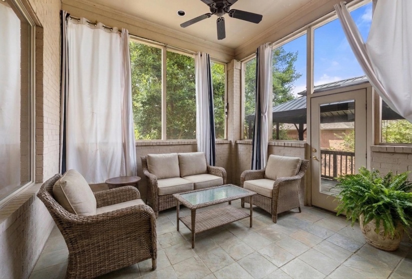 Screened porch featuring a ceiling fan, light-colored brick walls, and durable tile flooring