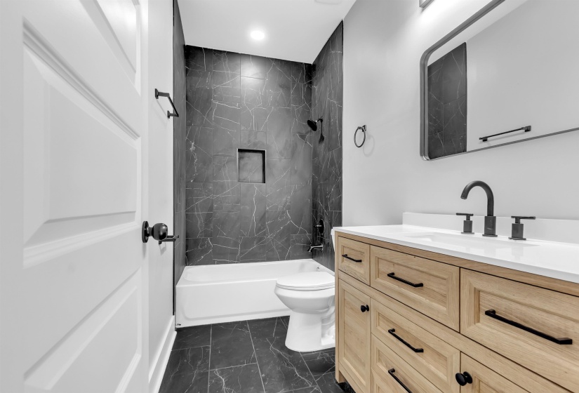 Bathroom featuring a light wood-finish vanity with a white countertop and matte black fixtures