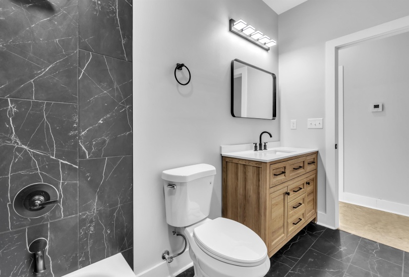 Bathroom featuring a wood-finish vanity with white countertop, rectangular sink, and matte black faucet