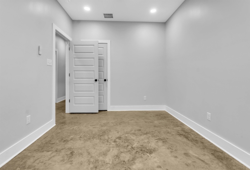 Interior space with light gray walls, white baseboards, and textured concrete flooring