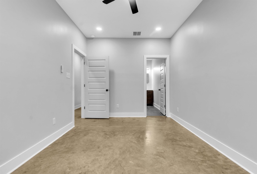 Spacious room featuring concrete flooring, light gray walls, white trim, and recessed lighting