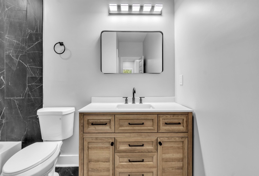 Wood-finish vanity with white countertop, undermount sink, and matte black faucet