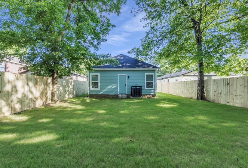 Expansive grassy yard enclosed by a newly installed wooden privacy fence