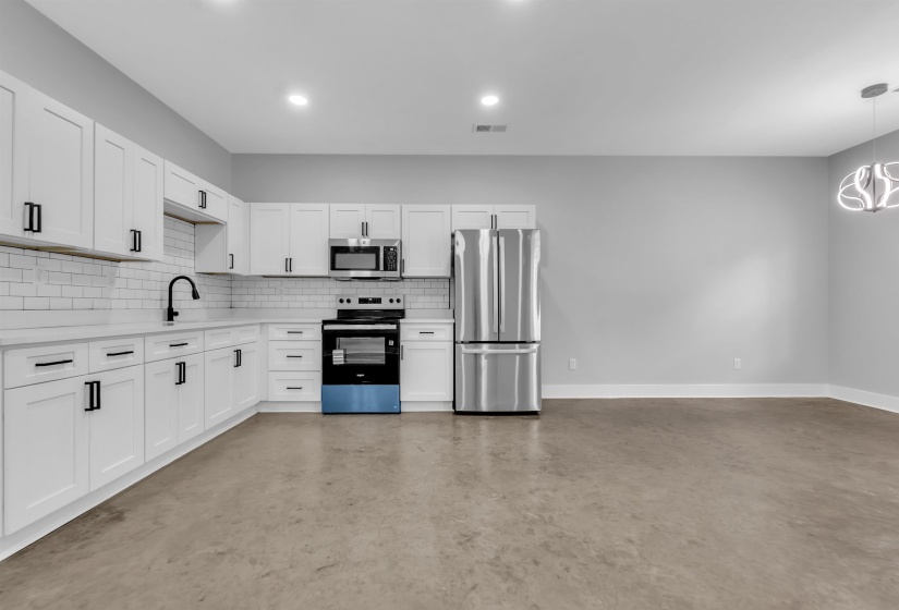 Modern kitchen featuring white shaker cabinetry with black hardware, subway tile backsplash, stainless steel appliances, and a matte black faucet