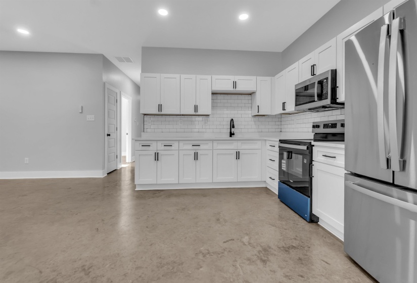 Modern kitchen featuring white shaker cabinetry, stainless steel appliances, subway tile backsplash, and a matte black faucet