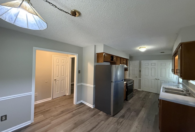 Kitchen featuring wood-finish flooring, warm wood cabinetry, a double basin sink, and a stainless steel refrigerator