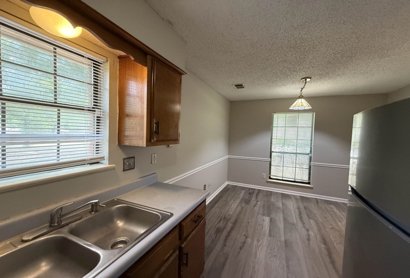 Kitchen area featuring double basin stainless steel sink, wood cabinetry, and a window with blinds