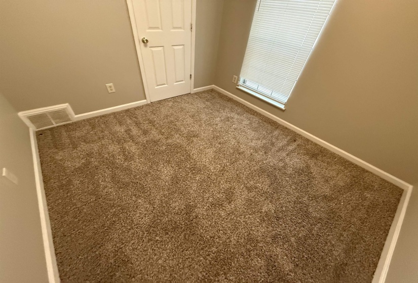 Carpeted room featuring a white door, neutral wall paint, and white baseboards