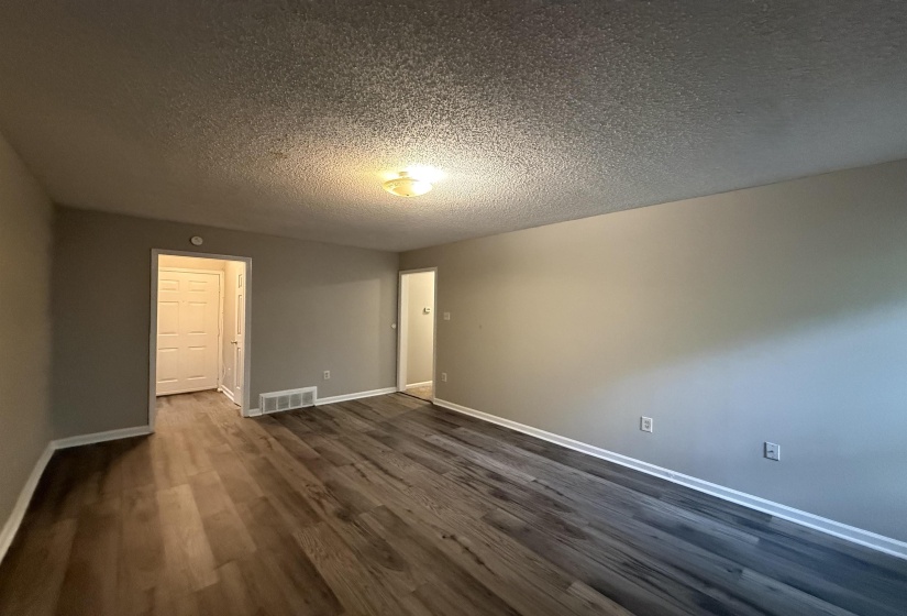 Spacious interior featuring wood-finish flooring, neutral wall tones, white baseboards, and a flush mount ceiling light