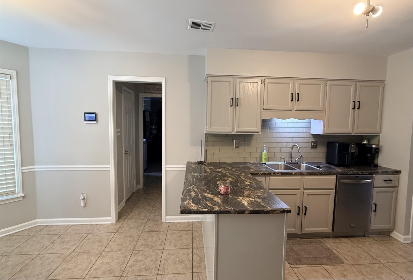 Kitchen featuring light-toned cabinetry, a dark patterned countertop, and a subway tile backsplash