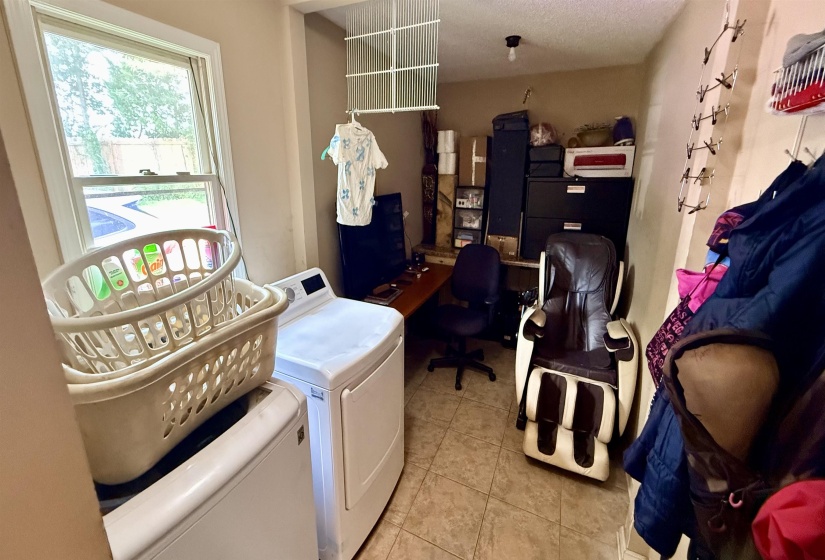 Utility room featuring a window, tile flooring, and a washer and dryer