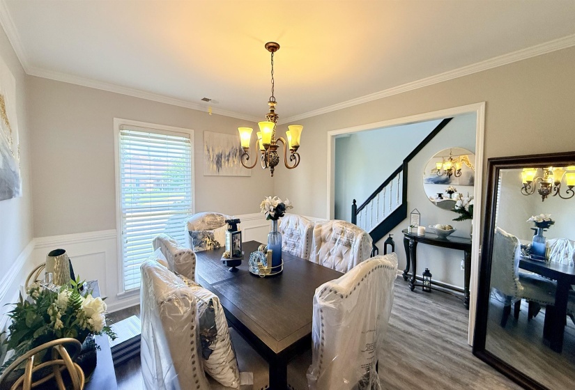 Dining area featuring crown molding, a decorative chandelier, and a large window with blinds
