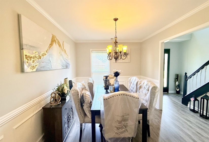 Dining area featuring a contemporary chandelier, crown molding, and wainscoting