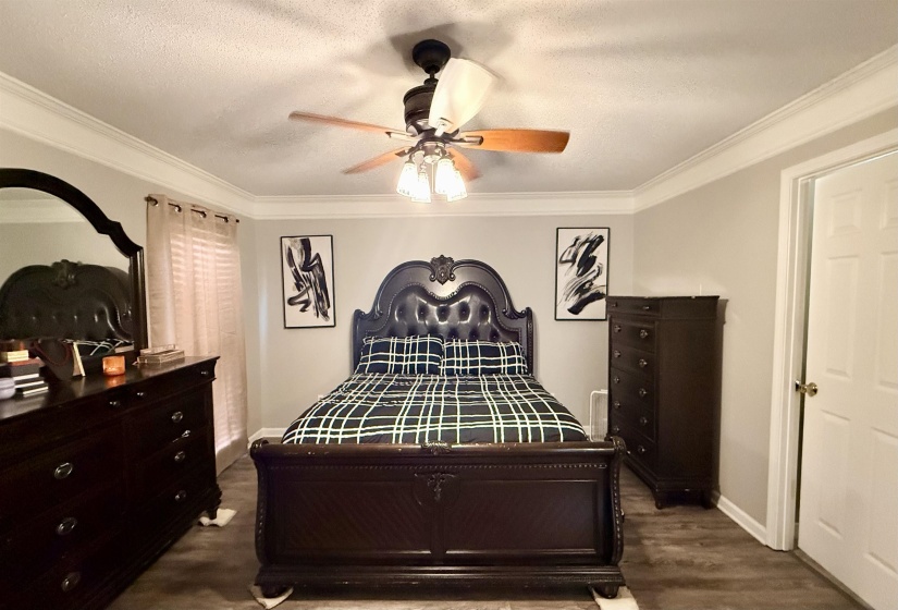Bedroom featuring wood-finish flooring, crown molding, and a ceiling fan with integrated lighting