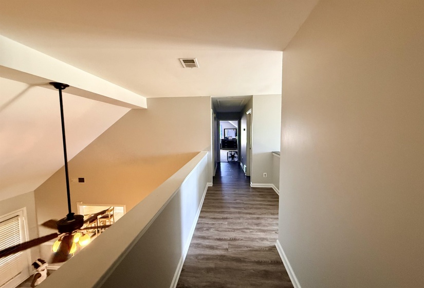 Upper-level hallway featuring wood-finish flooring and light neutral wall tones