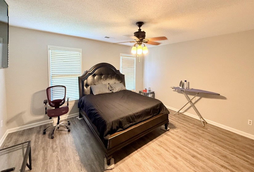 Spacious room featuring wood-finish flooring, light-colored walls, and a ceiling fan with integrated lighting