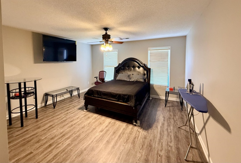 Spacious room featuring wood-finish flooring, neutral-toned walls, and a ceiling fan with light fixture