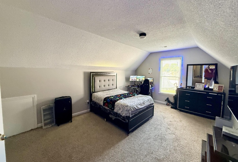 Attic room featuring a window, sloped ceilings, light gray wall paint, and wall-to-wall carpeting