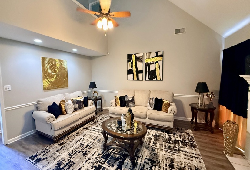Living area featuring vaulted ceilings, wood-finish flooring, recessed lighting, crown molding, and a ceiling fan