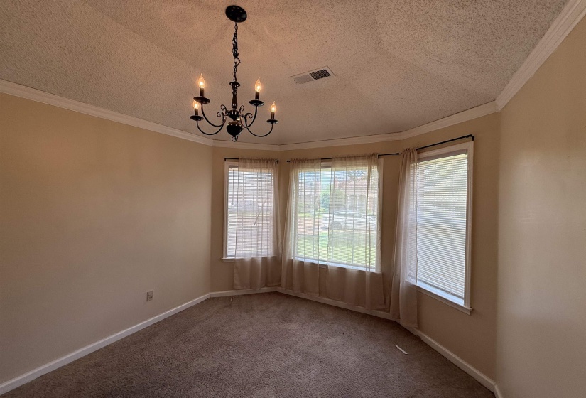 Bay window with multiple panels, crown molding, and a chandelier