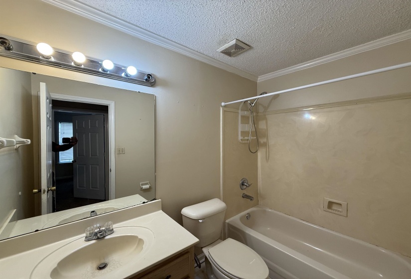 Full bathroom featuring a single vanity, integrated sink, and a combination shower and tub with a beige surround