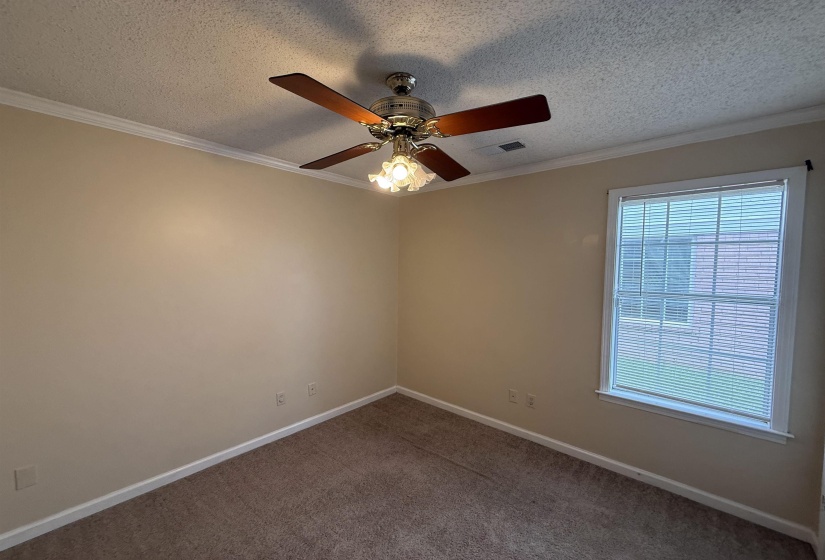 Neutral-toned room featuring a ceiling fan with light fixture, textured ceiling, crown molding, and a window with horizontal blinds
