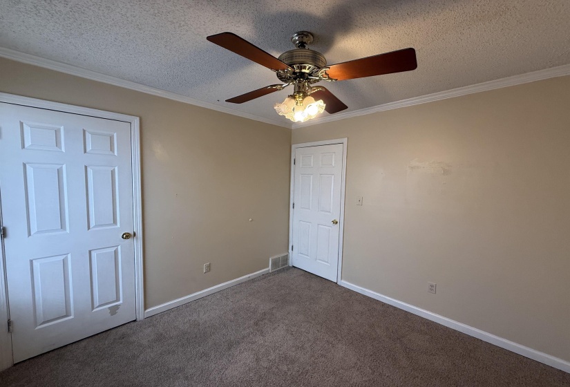Room featuring neutral-toned walls, textured ceiling, and a ceiling fan with light fixture