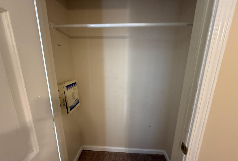 Interior closet featuring a white hanging rod, neutral-toned walls, and carpet flooring