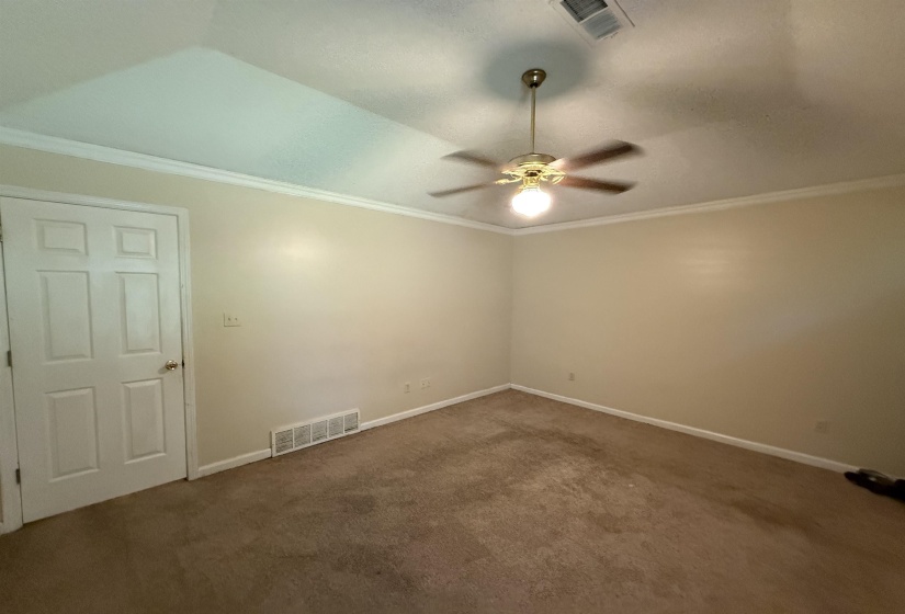 Room featuring neutral wall tones, crown molding, and a ceiling fan with integrated lighting