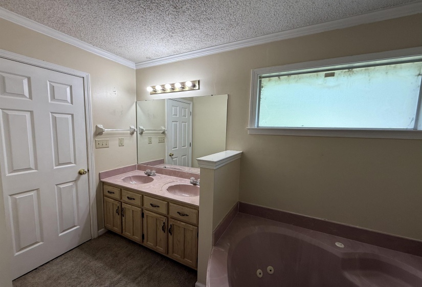 Bathroom featuring a dual vanity with integrated sinks, a built-in jetted tub, and overhead lighting