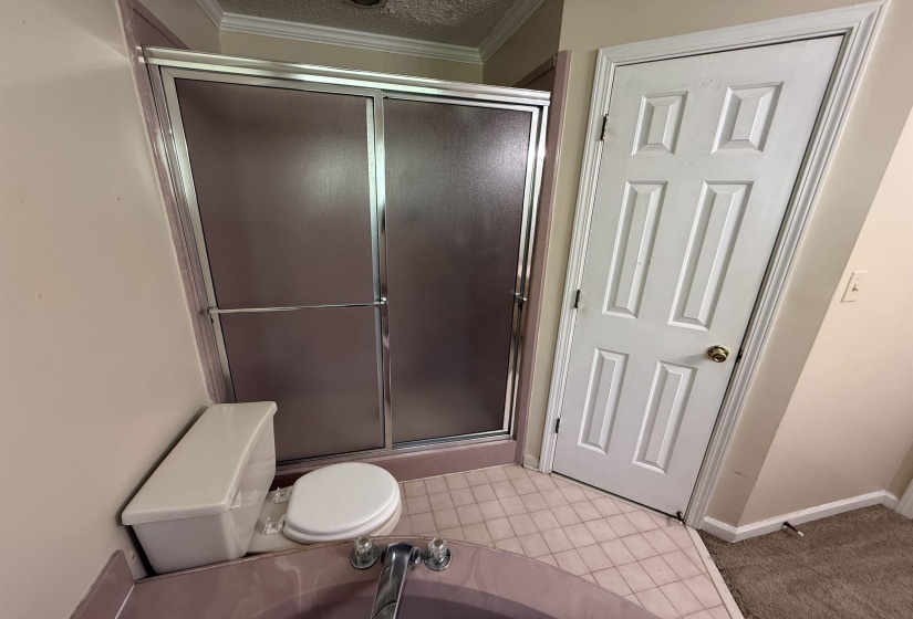 Bathroom featuring a glass-enclosed shower, a white toilet, and tile flooring