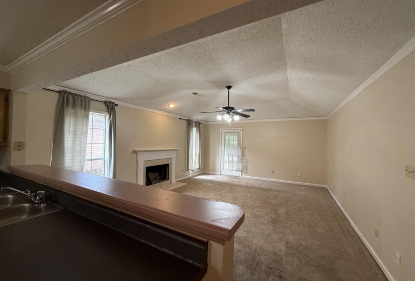 Spacious living area featuring a vaulted ceiling and crown molding