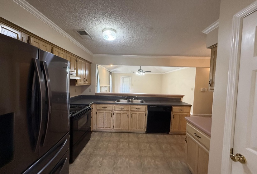 Kitchen featuring wood-finish cabinetry, dark countertops, and tile-style flooring