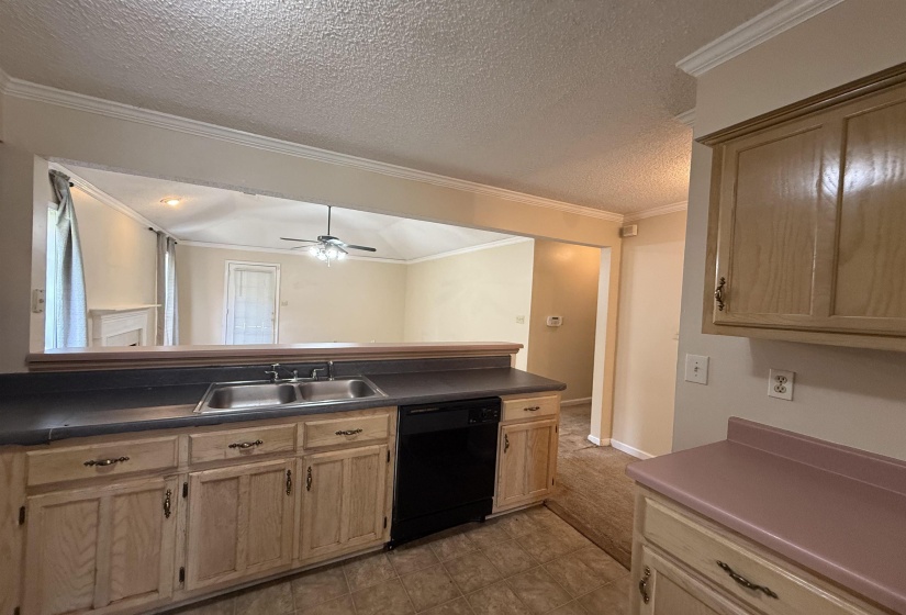 Kitchen with dual basin stainless steel sink, black dishwasher, and wood-finish cabinetry