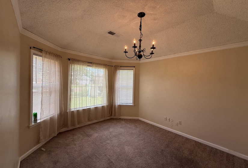 Bay window with multiple panels, crown molding, a black chandelier, wall-to-wall carpeting, and light-toned walls