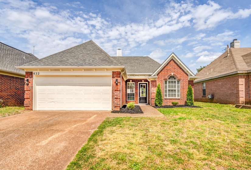 Brick exterior home featuring an attached two-car garage, a covered front entry, and an arched window