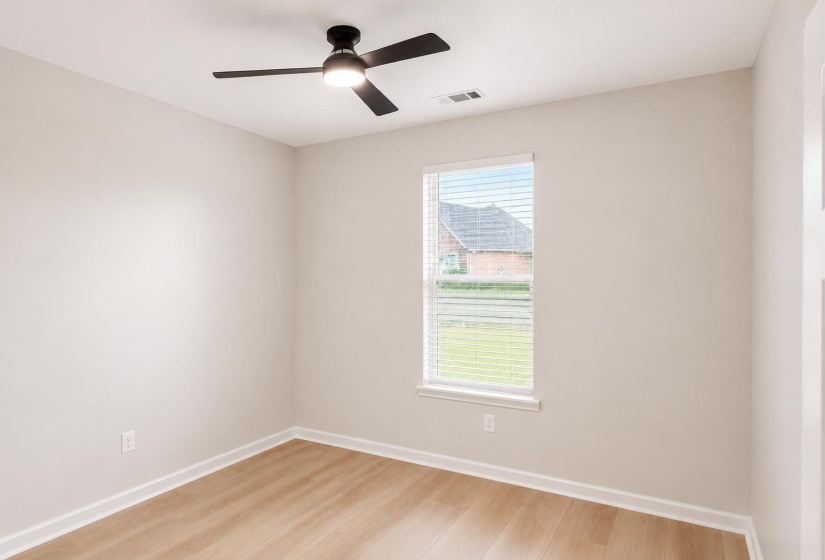Neutral-toned room featuring wood-finish flooring, a contemporary ceiling fan with integrated lighting, and a window with blinds