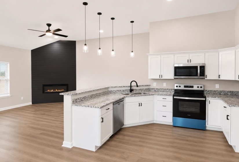 Modern kitchen featuring white cabinetry, granite-style countertops, and stainless steel appliances