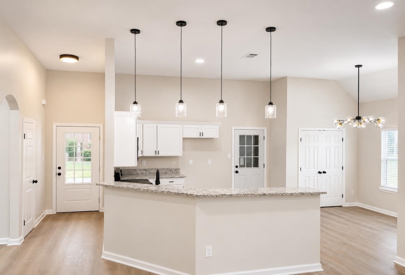 Modern kitchen featuring white cabinetry, granite countertops, and a breakfast bar with four pendant lights