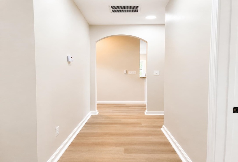 Hallway with wood-finish flooring, light neutral wall paint, and white baseboards