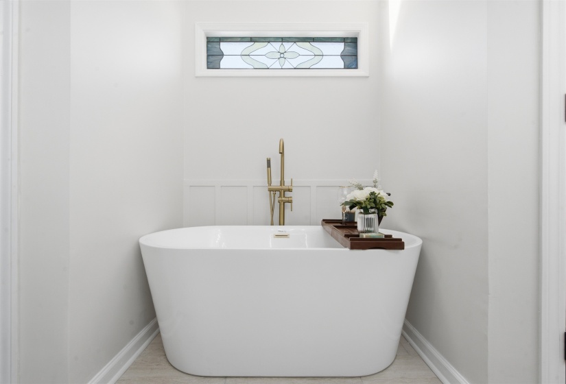 Freestanding soaking tub with a floor-mounted brass faucet