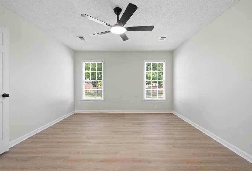 Spacious room featuring wood-finish flooring, light neutral walls, and a modern ceiling fan with integrated lighting