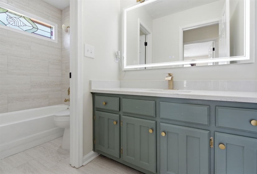 Bathroom vanity featuring a quartz countertop, integrated sink, and gold-finish faucet