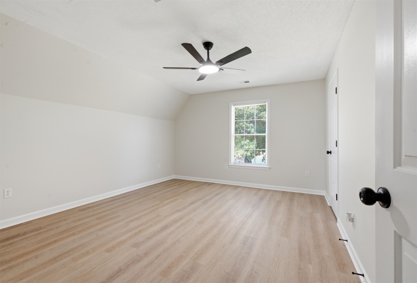 Room featuring wood-finish flooring, a contemporary ceiling fan with integrated lighting, a double-hung window, and a crisp white color palette