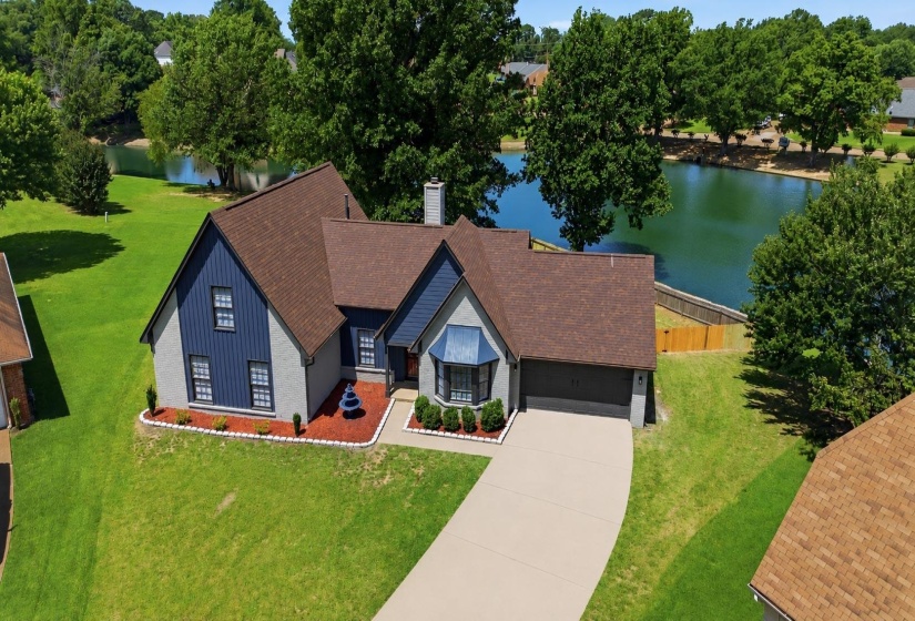 Waterfront property with a gray and blue exterior, featuring a bay window, attached two-car garage, and a concrete driveway